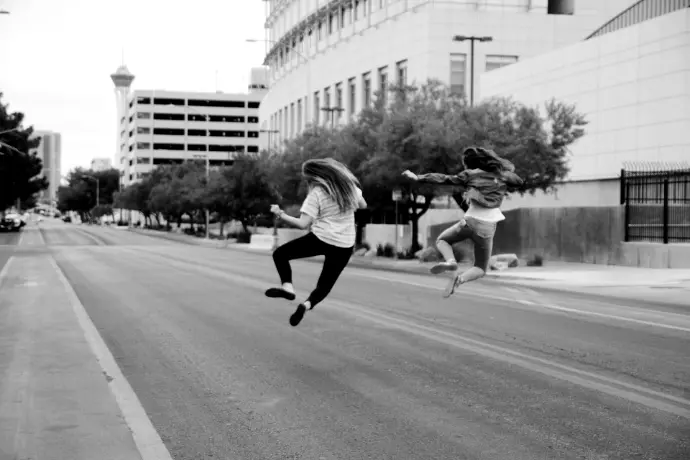 two woman jumping on the street during daytime