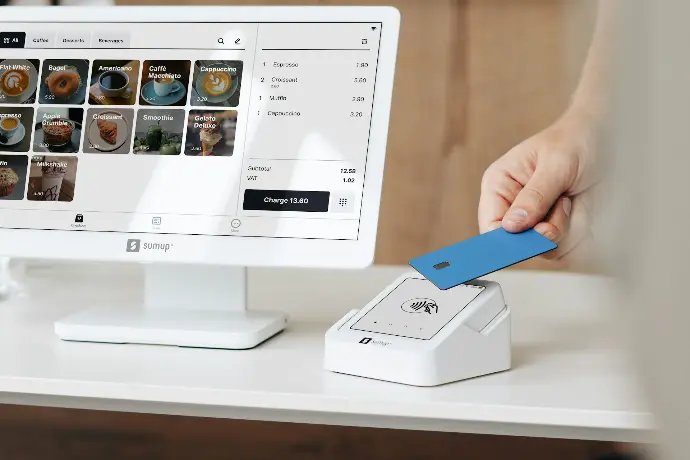 A person holding a blue card in front of a computer